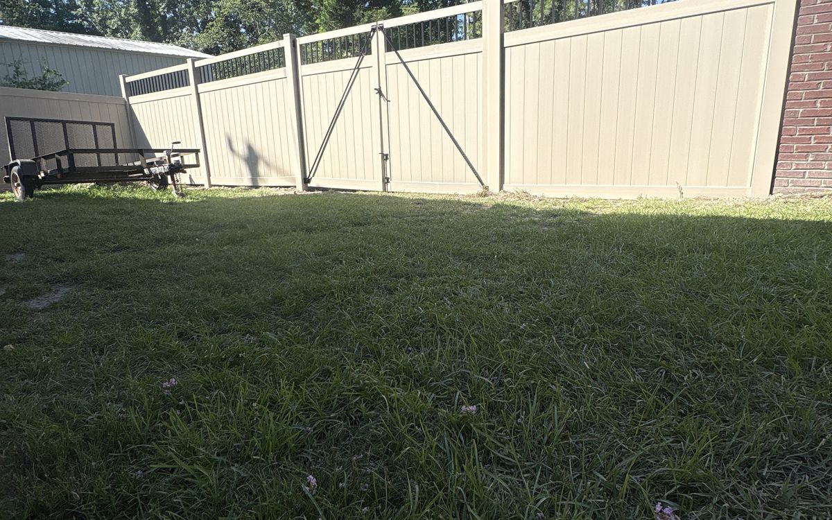 Adobe vinyl privacy fence with a black picket top and a walk gate beside a brick home in West Columbia, SC