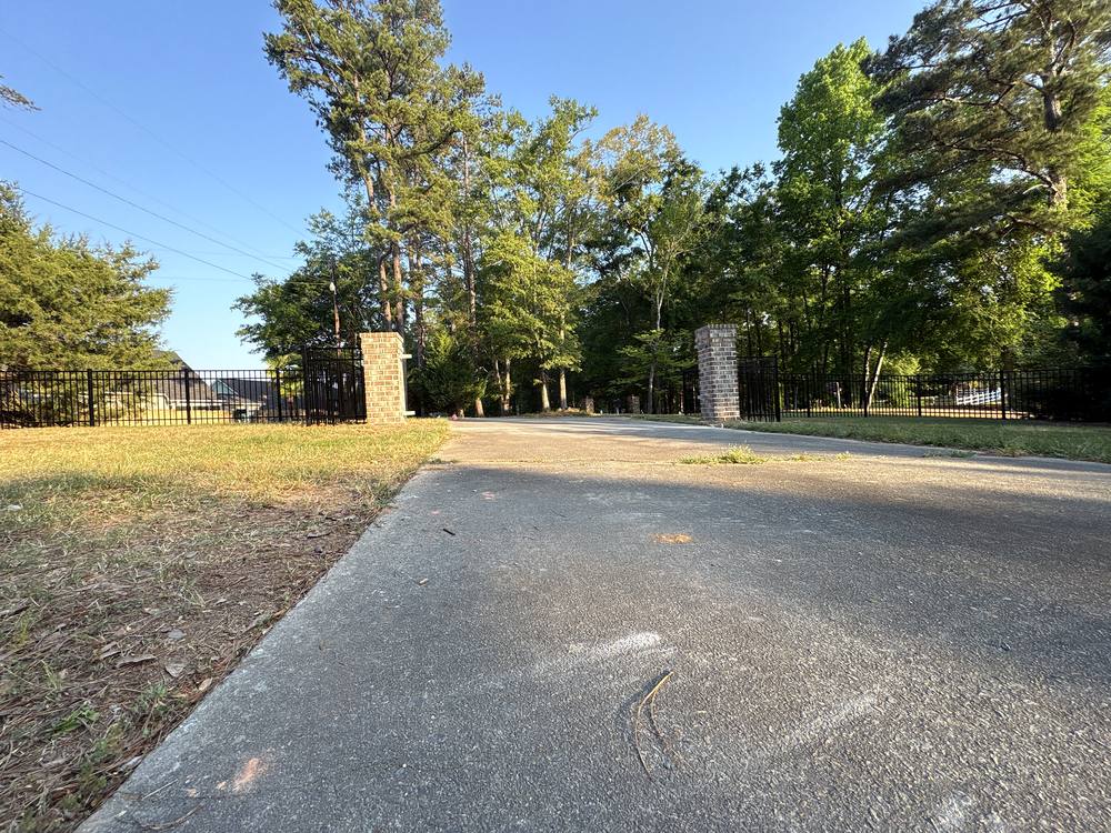 Black aluminum fence and driveway entrance between two brick pillars in the Midlands of South Carolina