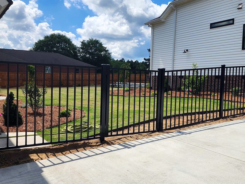 Commercial grade black aluminum fence beside a rose bed at a white farmhouse in Gilbert, SC