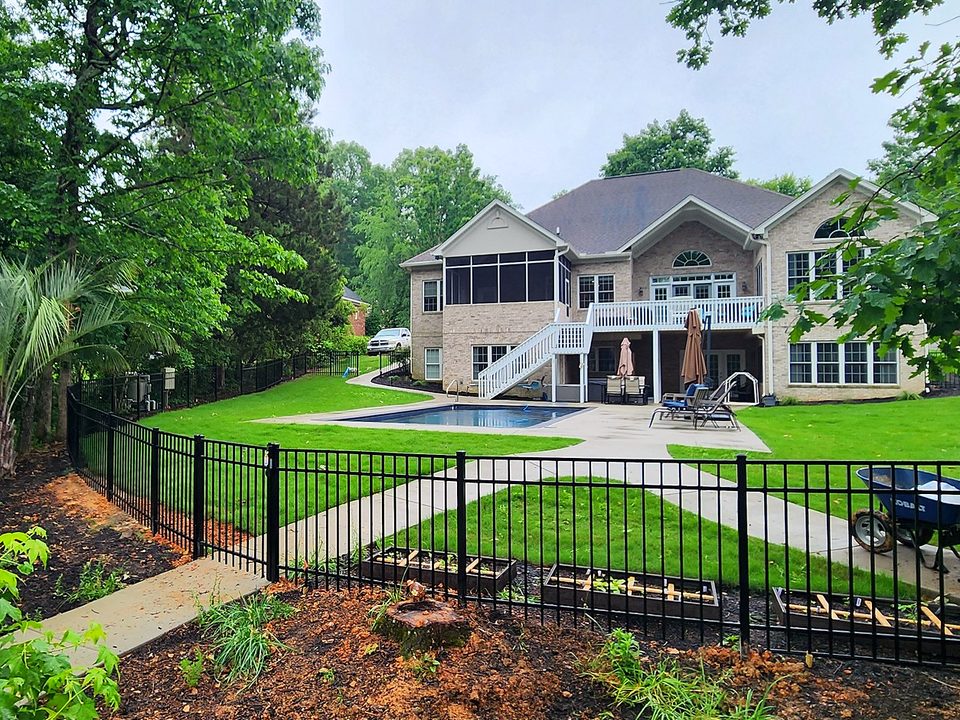 Black aluminum pool fence around a backyard pool behind a two story home in Lexington, SC
