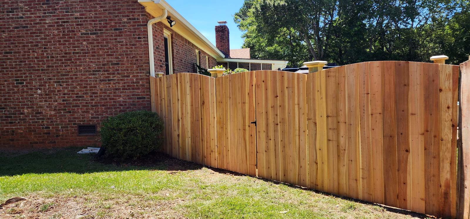 Cedar arch top wood privacy fence and matching gate along a brick home in the Midlands of South Carolina