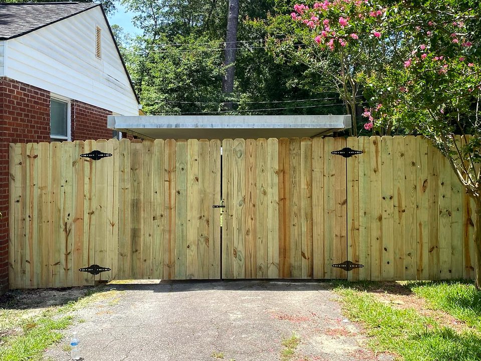 Custom wood double drive gate with black strap hinges across a driveway in West Columbia, SC
