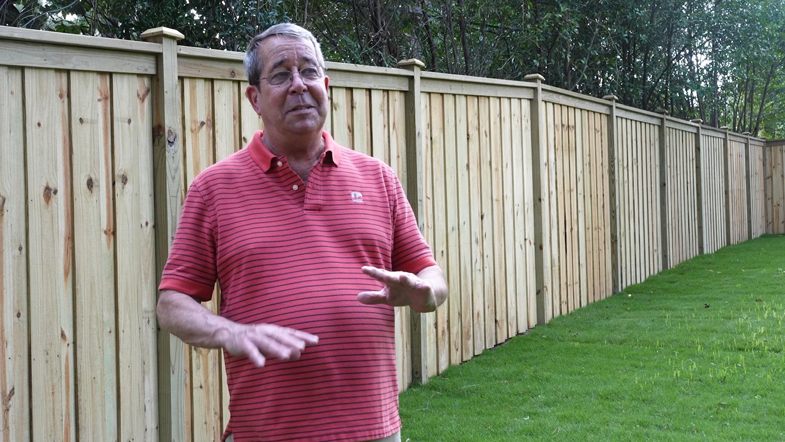 A Supreme Site Services customer standing in front of his new wood cap and trim privacy fence
