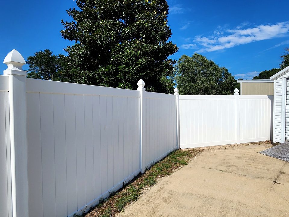 White vinyl privacy fence with finial post caps under a blue sky in West Columbia, SC