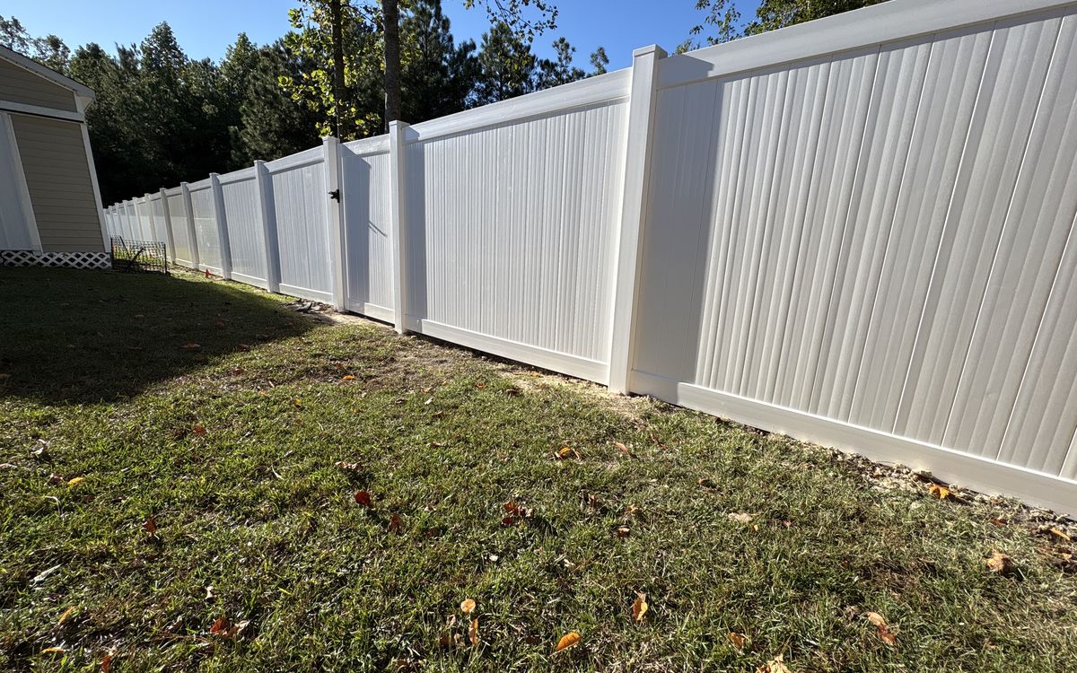 White vinyl privacy fence with a double drive gate along a lawn in the Midlands of SC