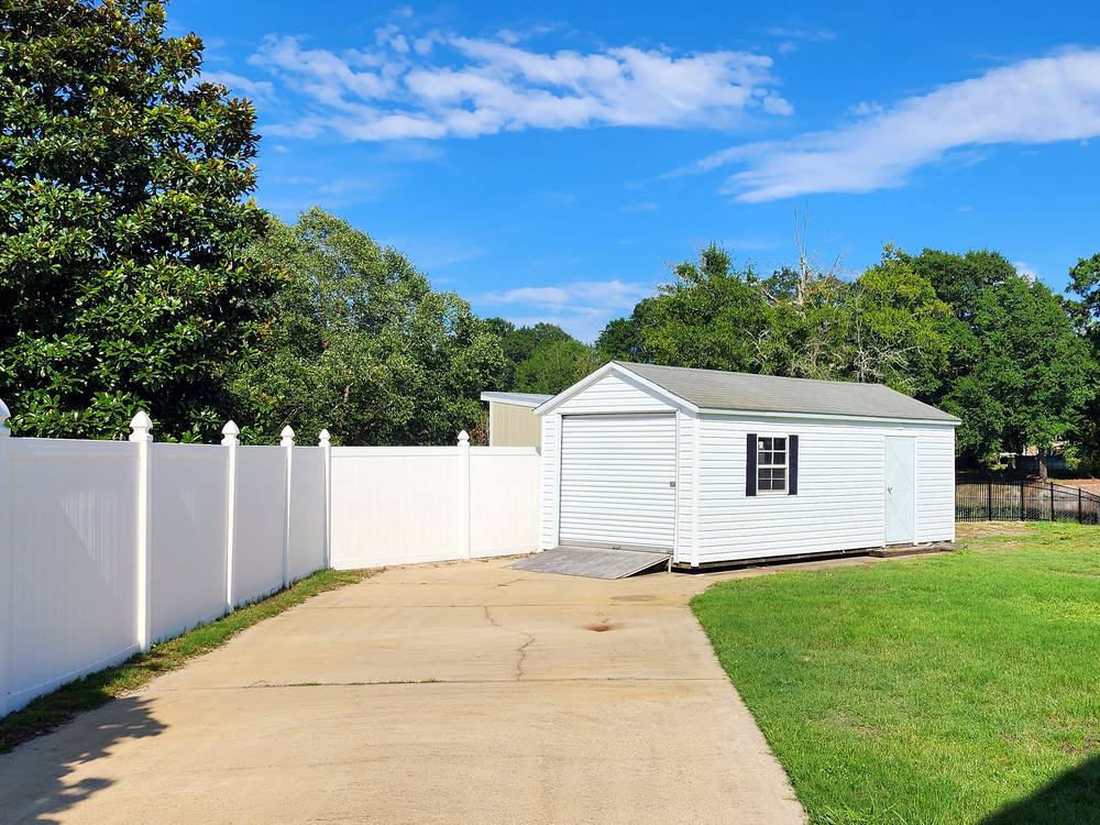 White vinyl privacy fence beside a driveway, shed and gazebo in the Midlands of South Carolina