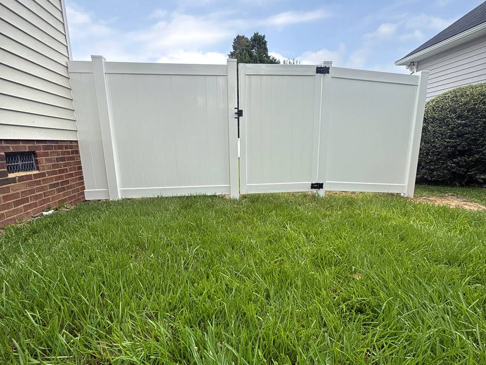 White vinyl privacy fence and gate along a side yard beside a brick home in Lexington, SC