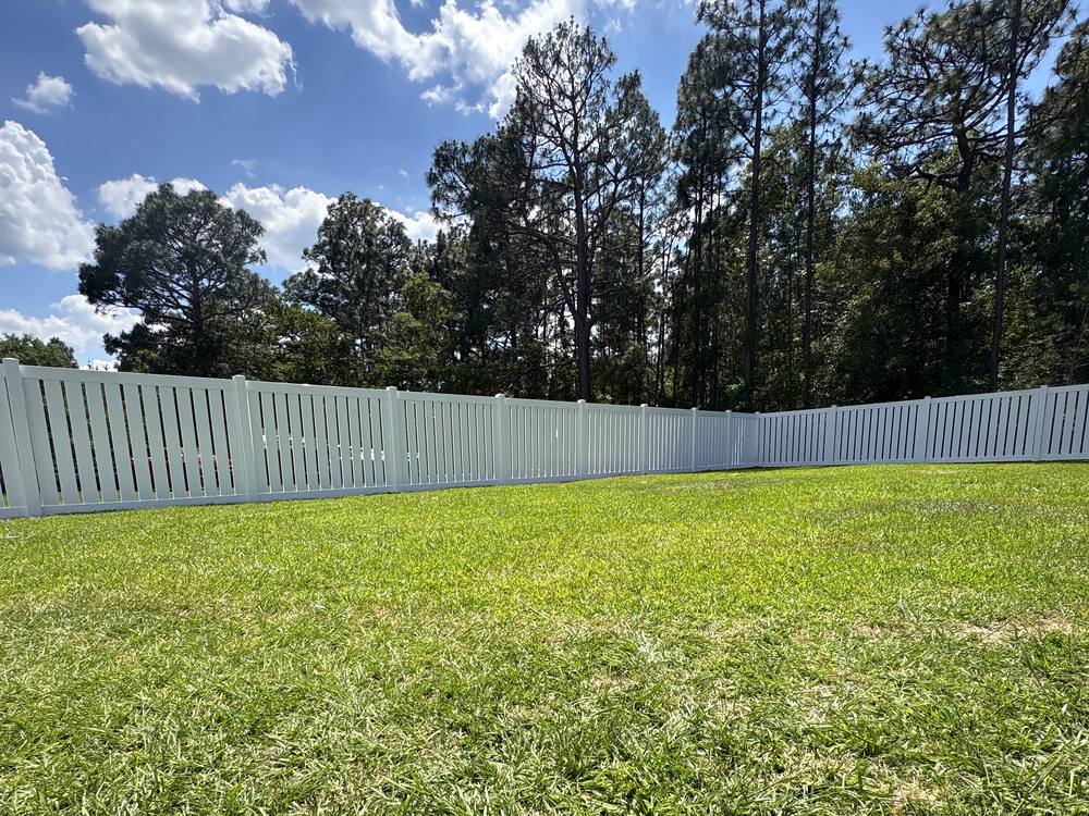 White vinyl semi privacy fence with a picket top along a green lawn in the Midlands of South Carolina