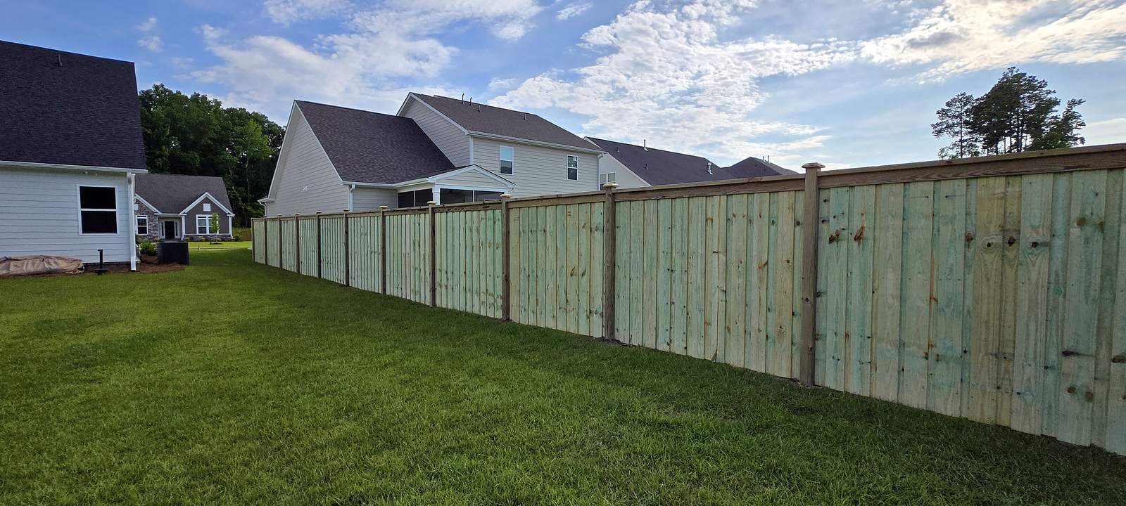 New board on board wood privacy fence with cap and trim along a mowed lawn in a Midlands subdivision