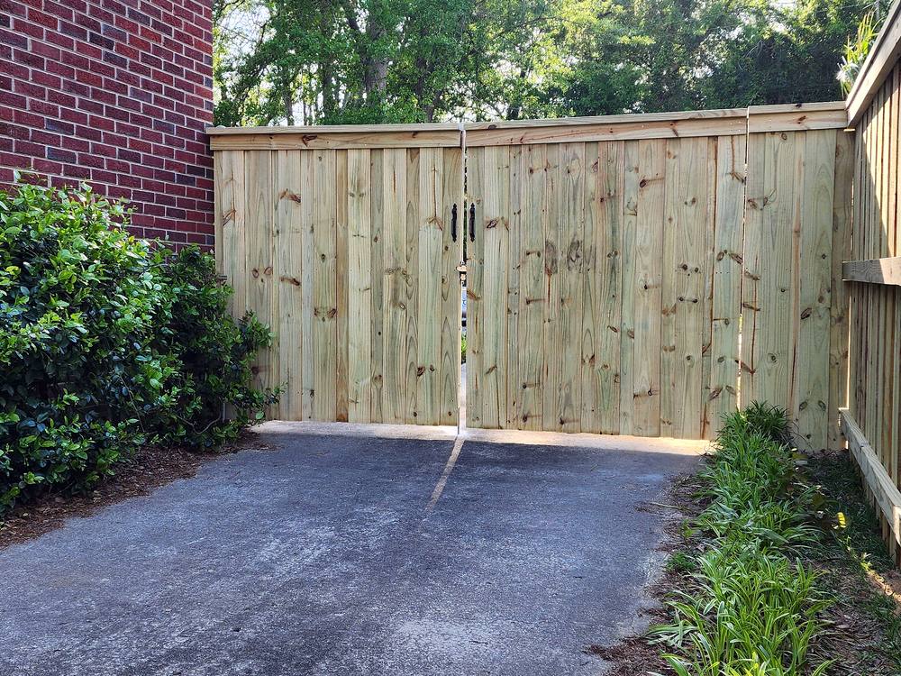 Closed wood privacy double drive gate beside a brick home in the Midlands of South Carolina
