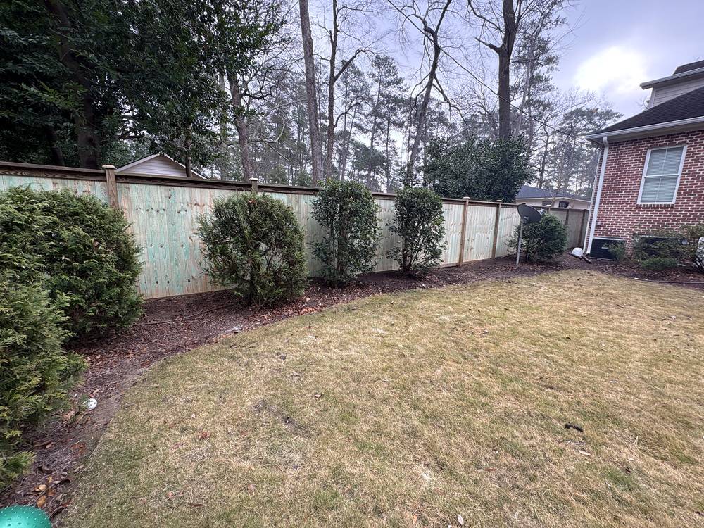 New wood privacy fence along a side yard with a row of shrubs in Columbia, SC