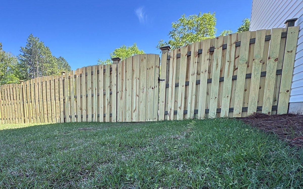 Wood shadowbox fence with a scalloped top beside a new home in Irmo, SC